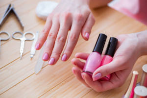 Mani con smalto rosa in primo piano, curate con una manicure impeccabile.