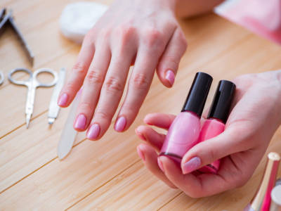 Mani con smalto rosa in primo piano, curate con una manicure impeccabile.