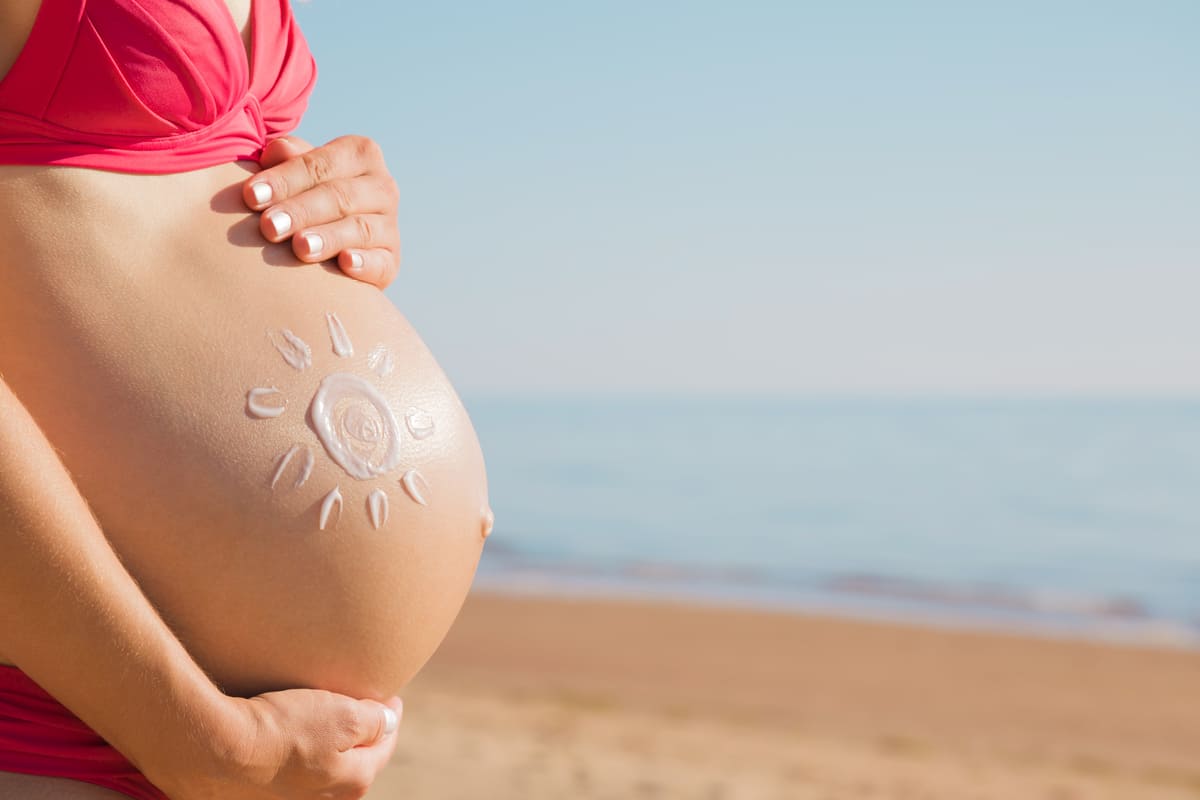 Donna incinta al sole sulla spiaggia