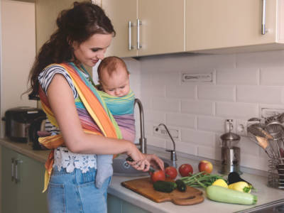 Mamma cucina con in braccio neonato