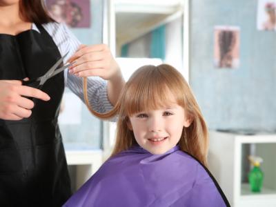 Bambina che taglia i capelli dalla parrucchiera