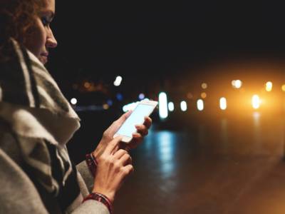 Ragazza utilizza lo smartphone tornando a casa di notte