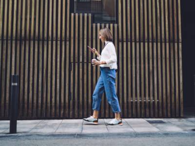 ragazza cammina marciapiede smarphone in mano