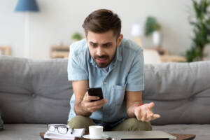 uomo guarda cellulare stupito confuso arrabbiato