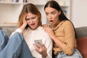 amiche leggono un messaggio e sono scioccate