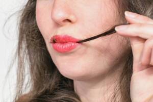 Una donna affetta da tricofagia porta una ciocca di capelli alla bocca