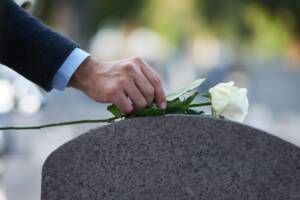 Rosa bianca lasciata su una lapide da un uomo in raccoglimento.
