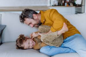 Un padre fa il solletico alla figlia e entrambi ridono di gusto