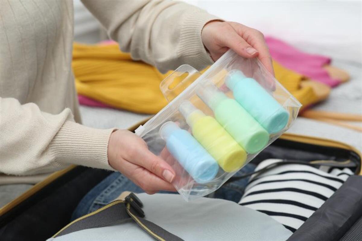 Donna ripone una trousse con prodotti cosmetici nella sua valigia