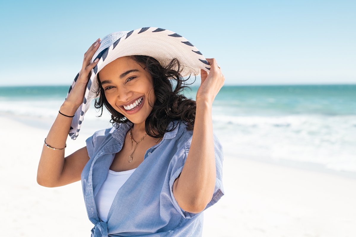 Ragazza in spiaggia con cappello al mare