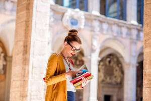 Una studentessa universitaria percorre i corridoi della facoltà con i libri stretti tra le braccia