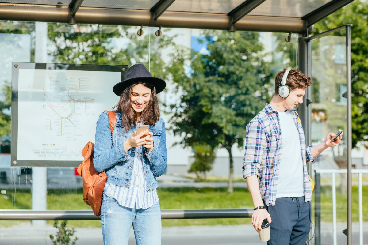 Dei ragazzi stanno usando lo smartphone mentre aspettano l'autobus