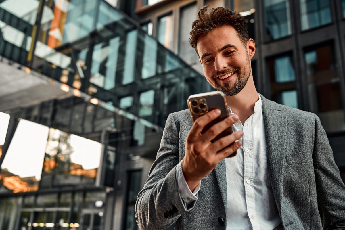 Giovane uomo con espressione sorridente mentre guarda il telefono