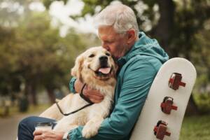 Un uomo anziano accarezza affettuosamente il suo cane al parco