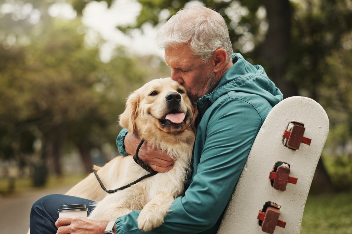 Un uomo anziano accarezza affettuosamente il suo cane al parco
