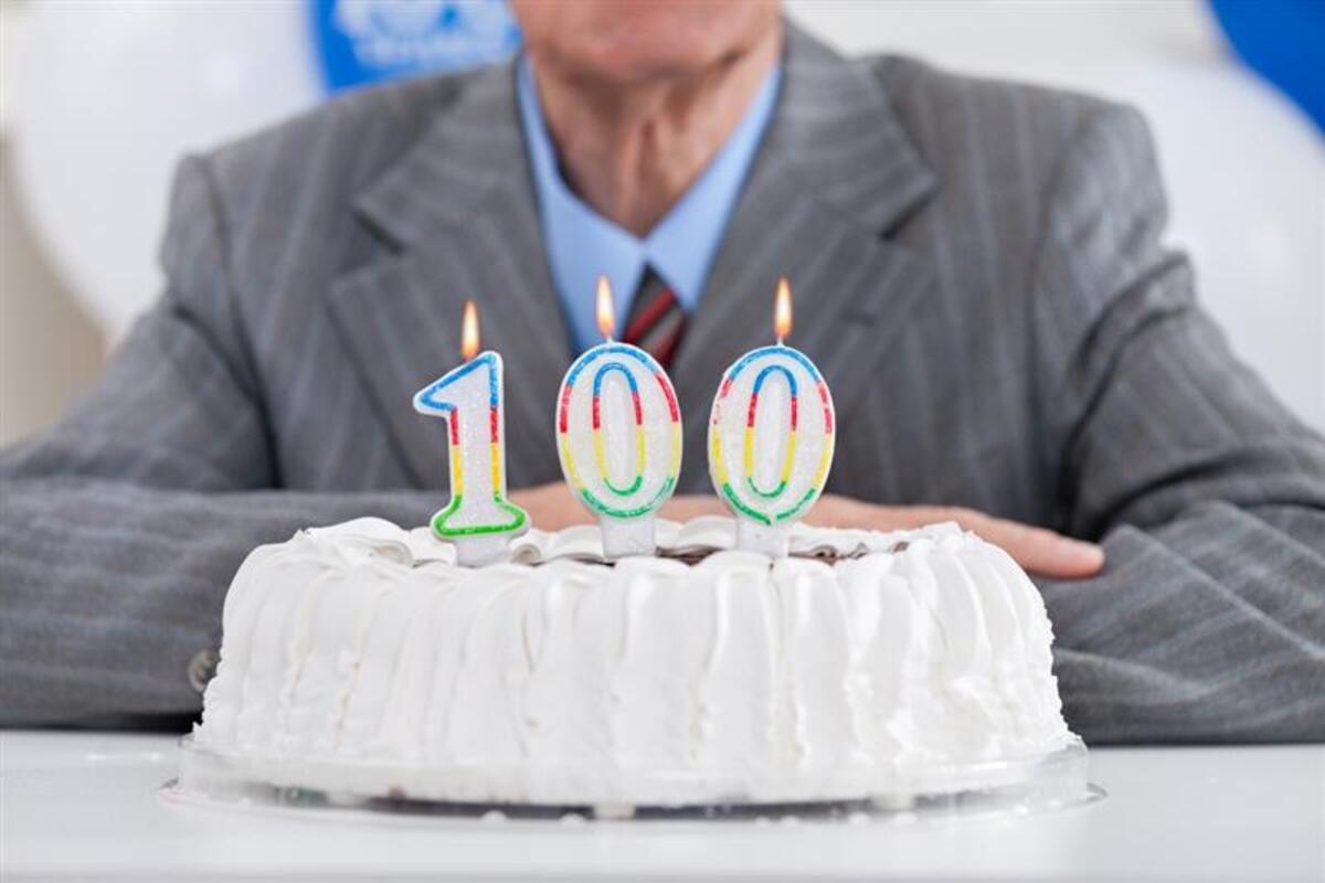 Uomo al suo compleanno con la torta da 100 candeline