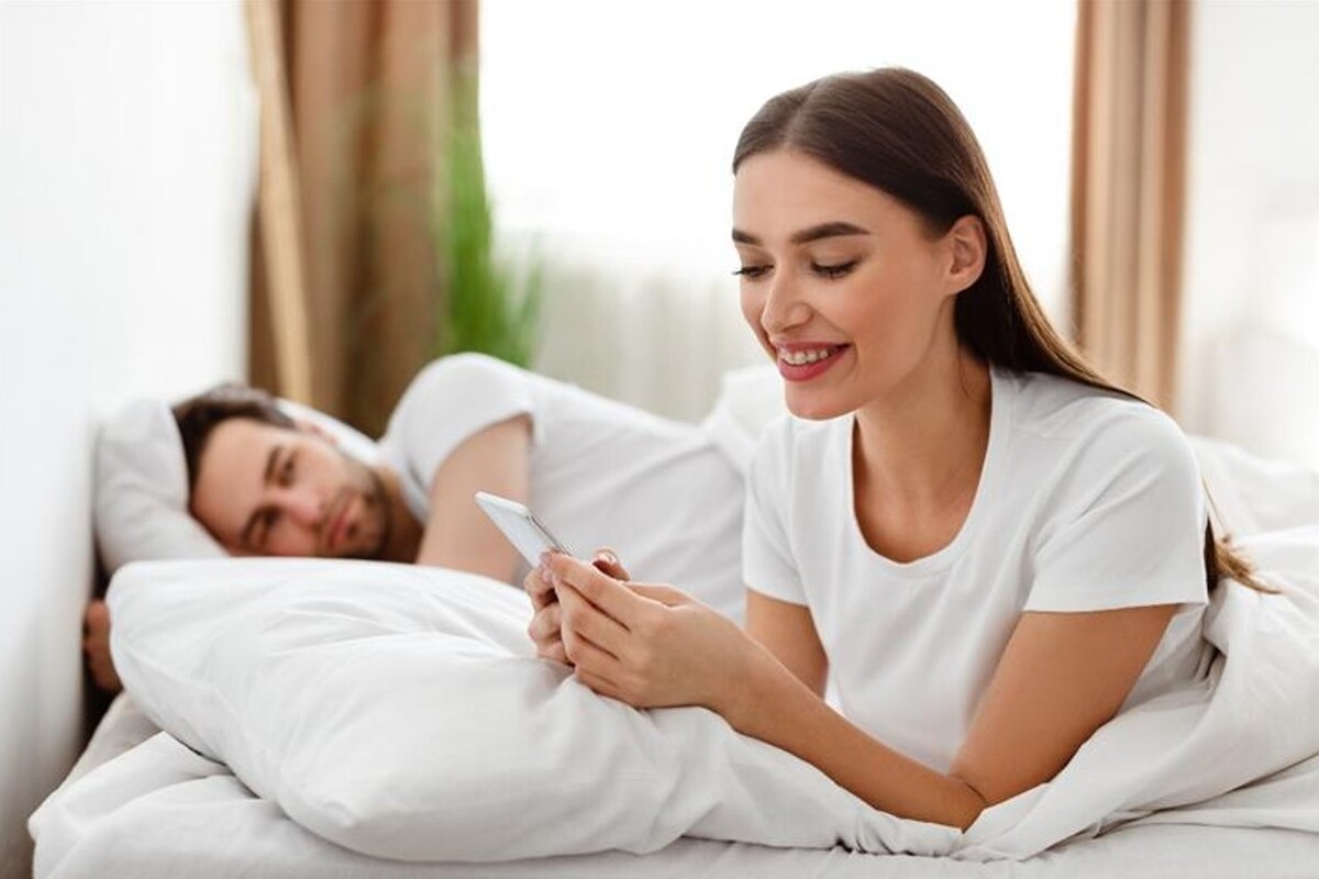 Mentre il suo fidanzato giace a letto, una ragazza chatta al cellulare con un'altra persona