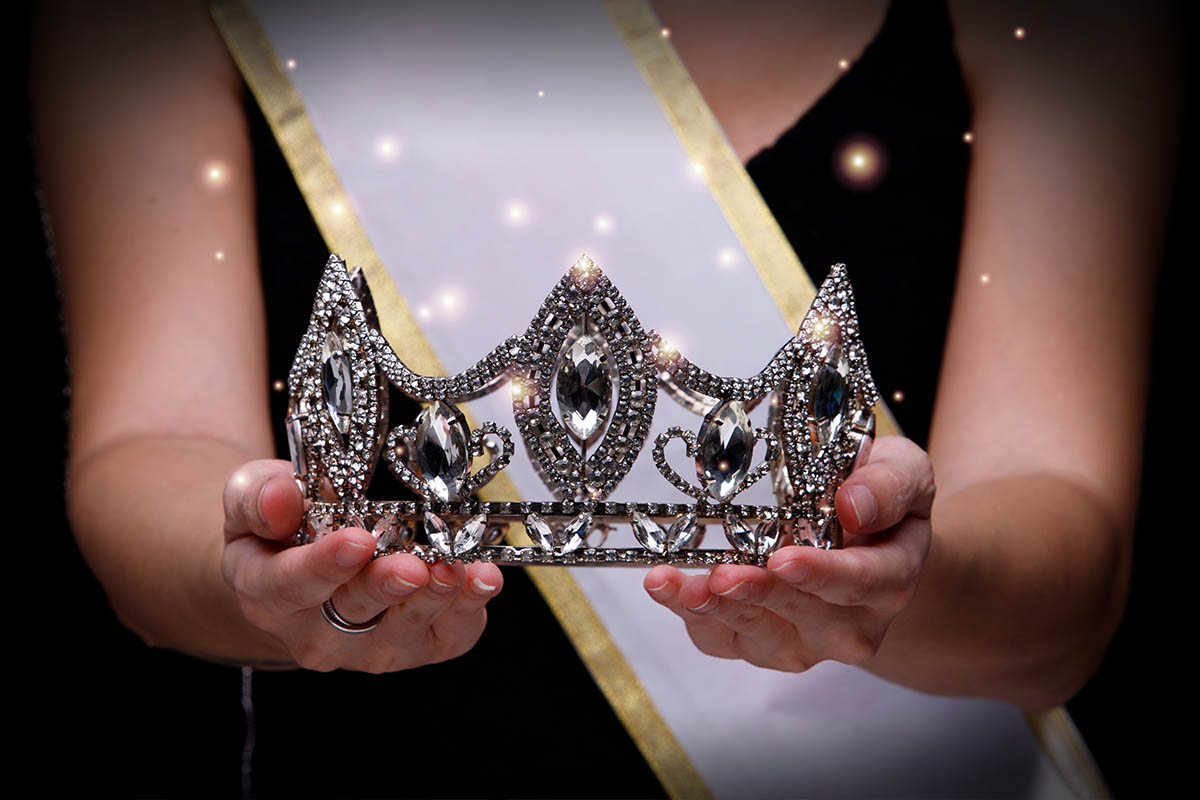 Miss che indossa una fascia e ha una tiara in mano