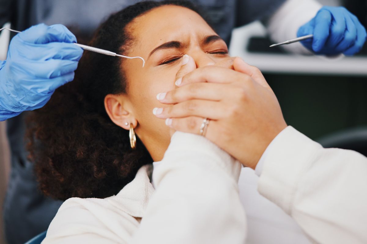 Una donna, terrorizzata dal dentista, si copre la bocca con le mani