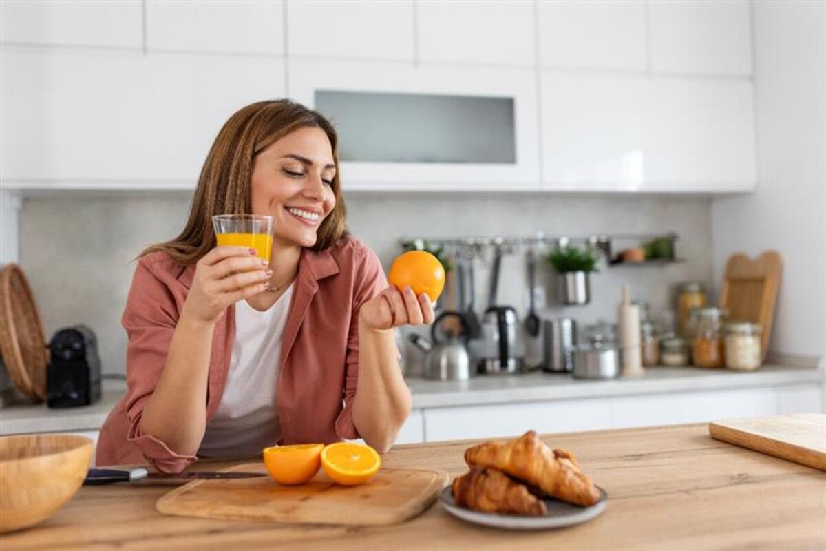Ragazza fa colazione con spremuta d'arancia e croissant