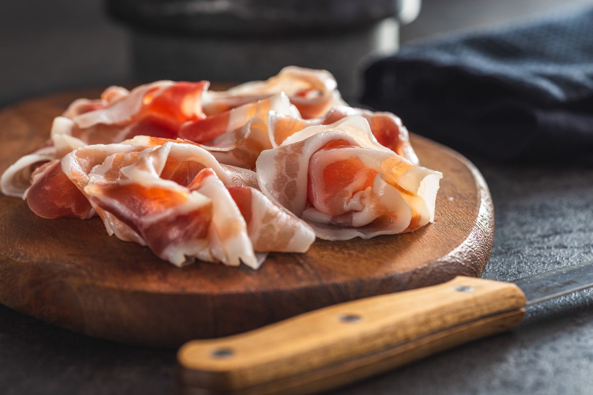 Fette di Pancetta su tagliere di legno con coltello