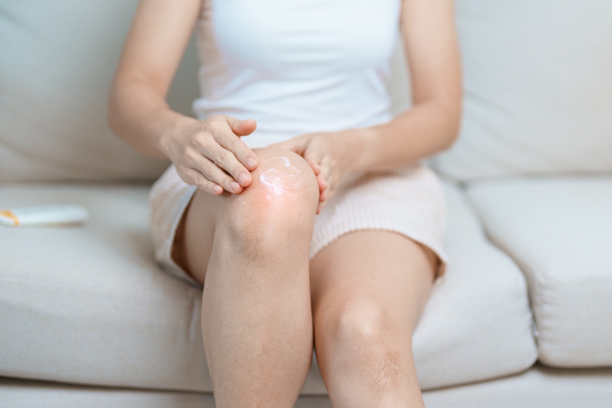 Donna che applica crema antinfiammatoria sul ginocchio dolorante.