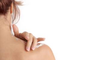 Donna che applica crema antinfiammatoria sulla spalla dolorante.