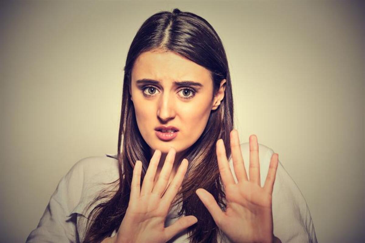 Una donna terrorizzata solleva le mani in un gesto protettivo