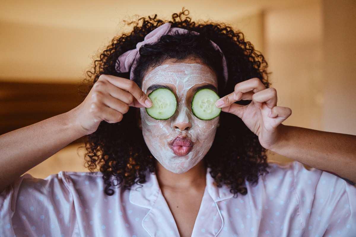Ragazza con una maschera sul viso e cetrioli sugli occhi