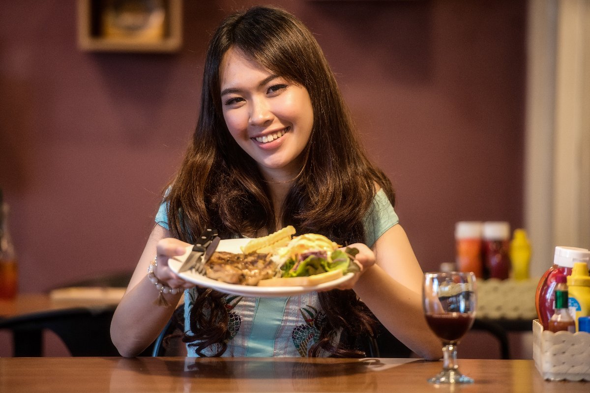 Ragazza sorridente che esibisce un piatto di cibo nutriente.