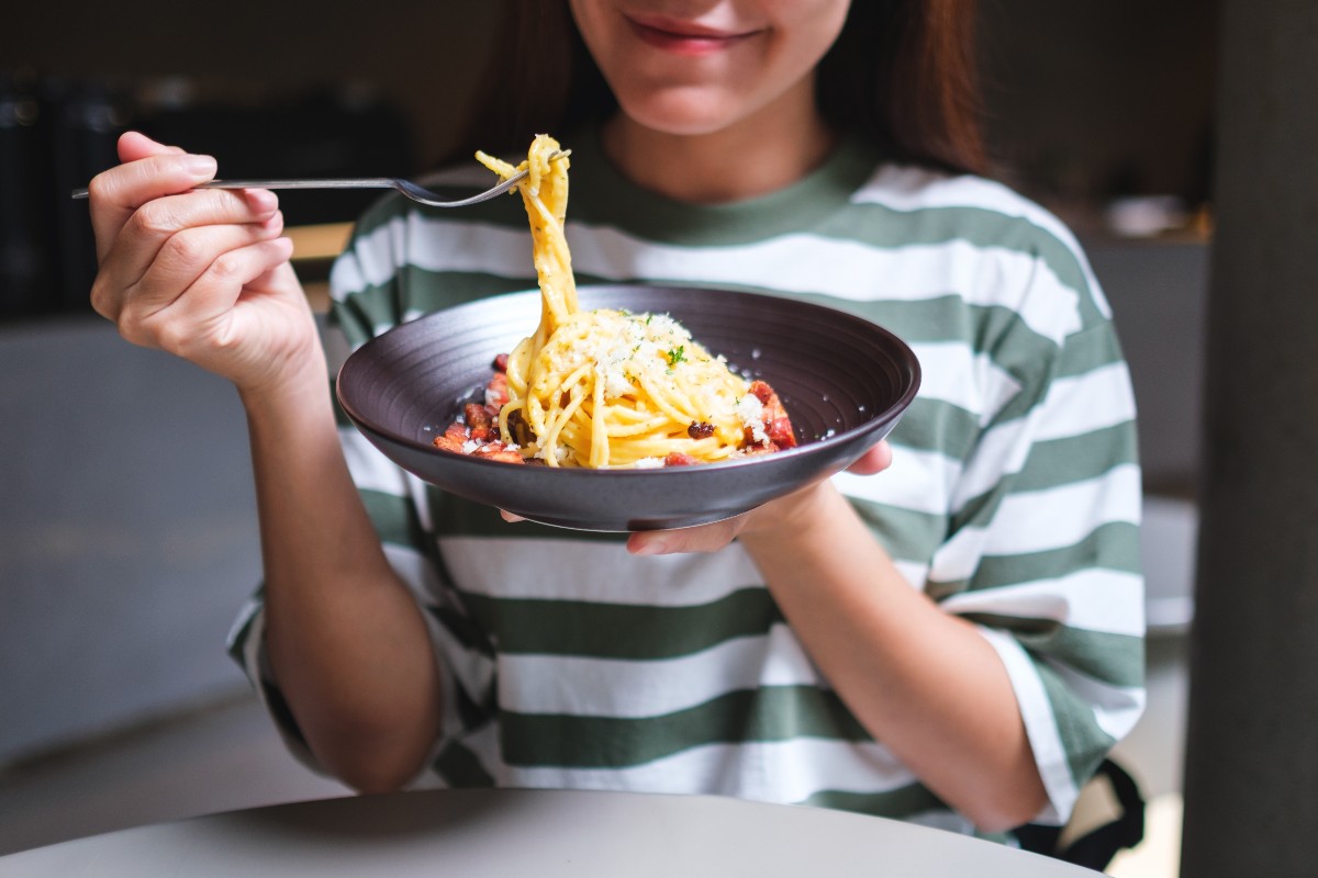 Una ragazza sta gustando un piatto di spaghetti