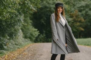 Look invernale femminile con cappotto elegante grigio e cappellino nero.