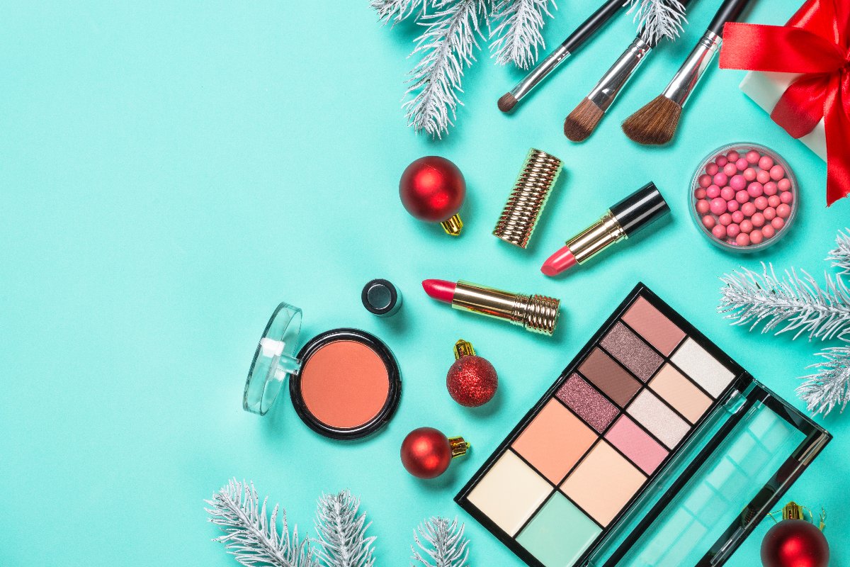 Makeup festivo: prodotti disposti su un tavolo circondato da decorazioni natalizie.