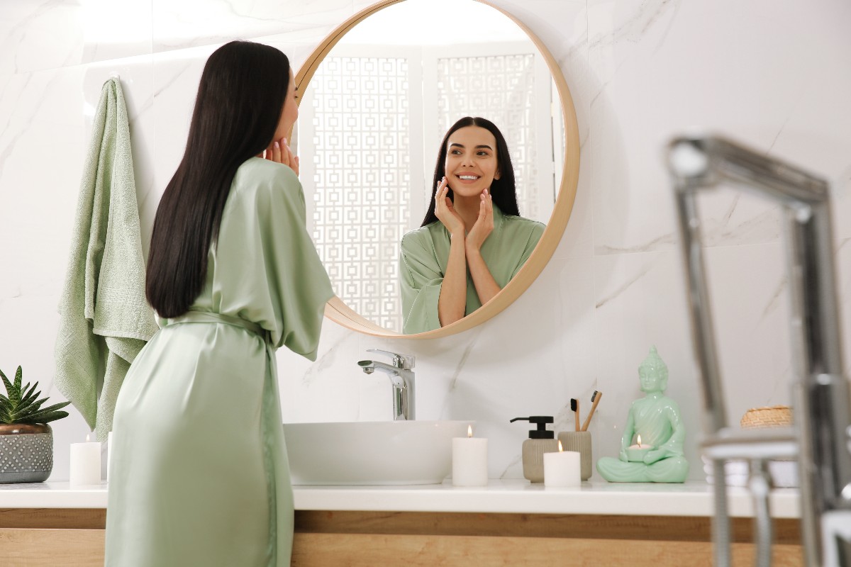 Giovane donna si osserva allo specchio nel bagno dal design moderno.