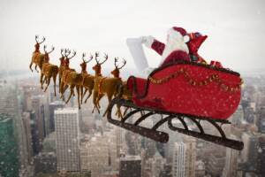 Babbo Natale sulla slitta con le renne sorvola la città