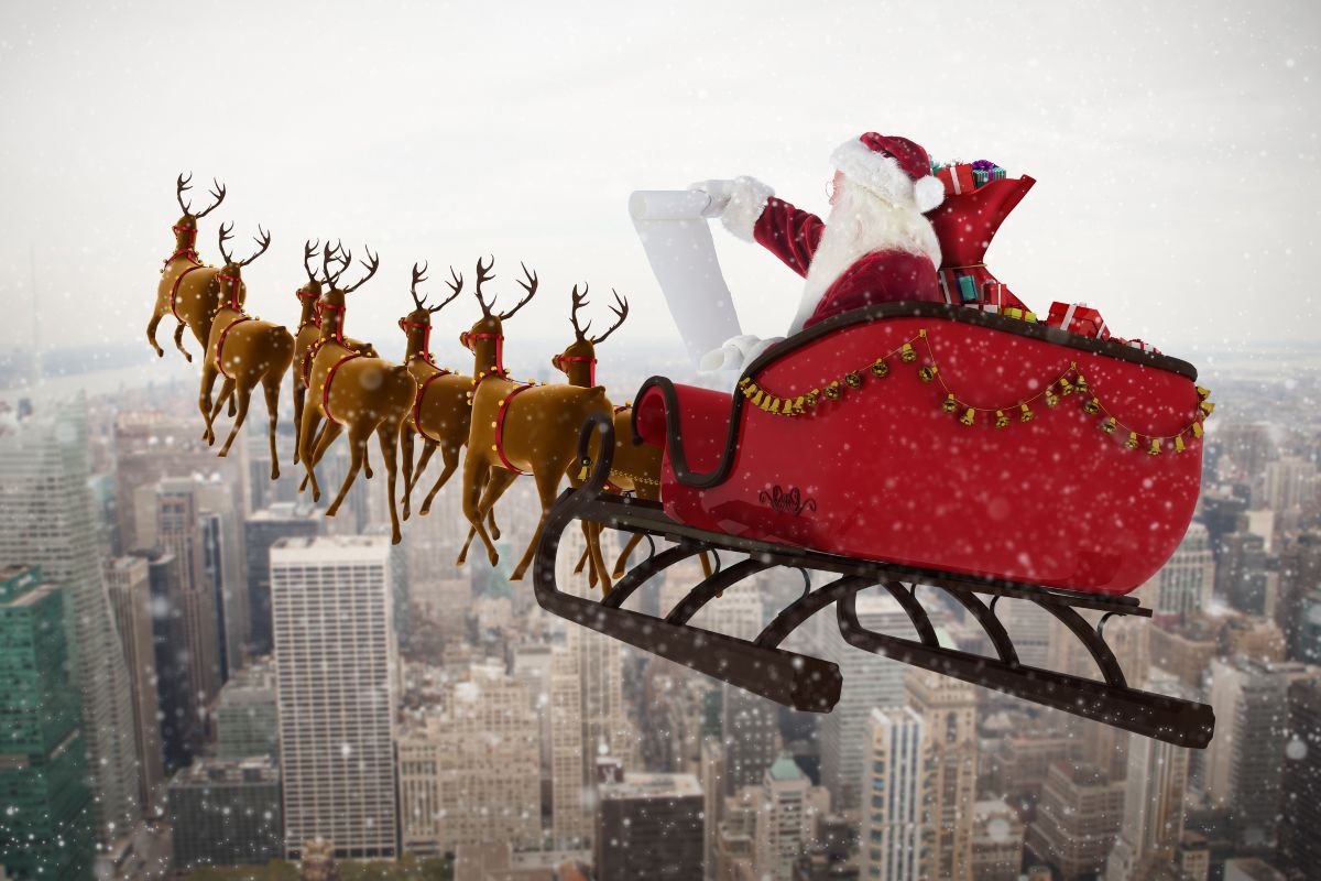 Babbo Natale sulla slitta con le renne sorvola la città