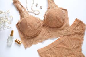 Set elegante: completo intimo color carne su fondo bianco con profumo e gioielli.