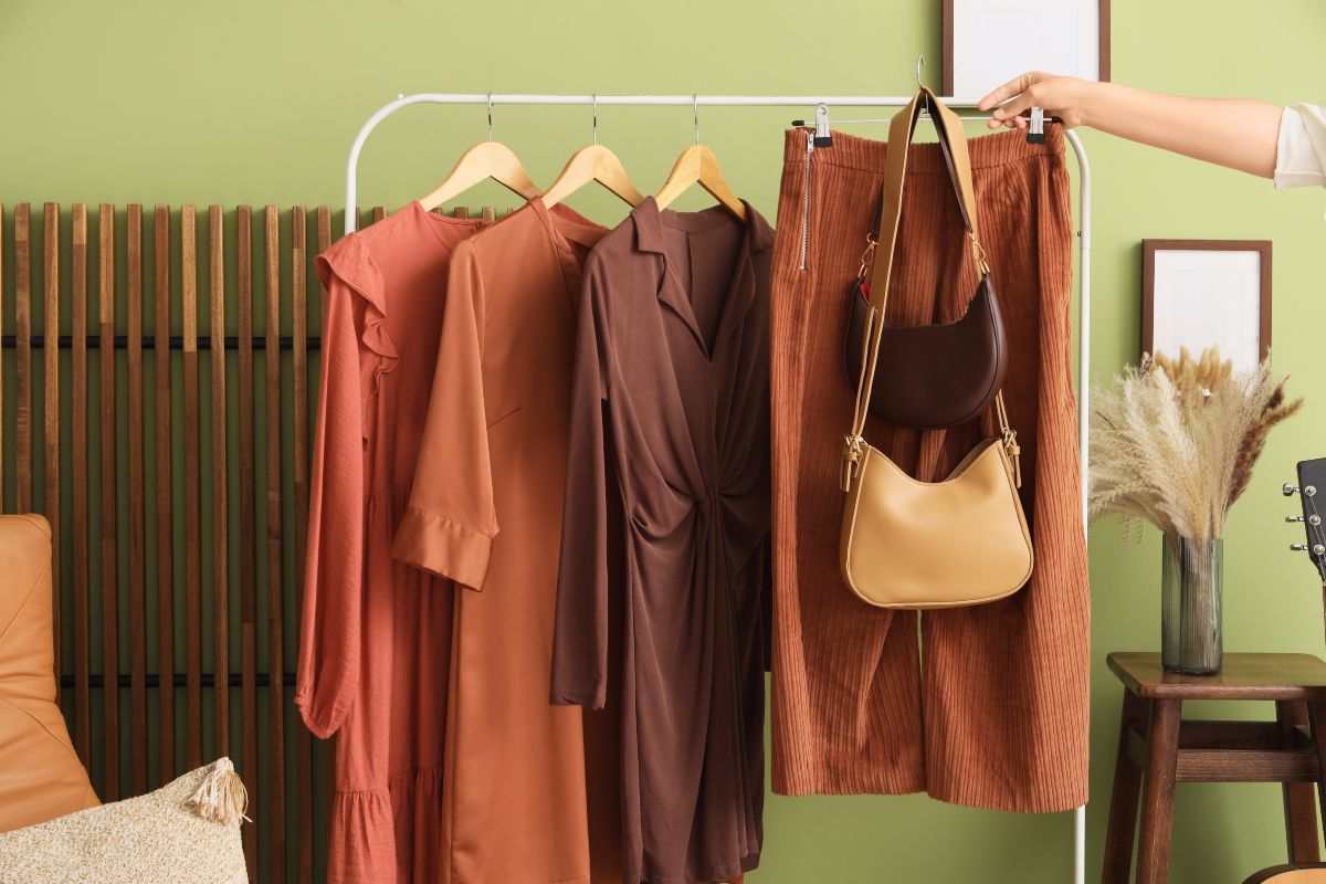 Guardaroba dai toni caldi: abiti e accessori disposti ordinatamente su toni del marrone, arancio e ocra.