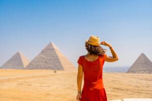 Ragazza in abito rosso di spalle mentre osserva le Piramidi di Giza in Egitto.