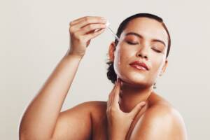 Una donna che applica del siero all'acido ialuronico sul viso.