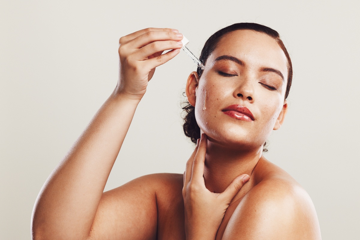 Una donna che applica del siero all'acido ialuronico sul viso.