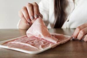 Ragazza mangia prosciutto cotto a fette