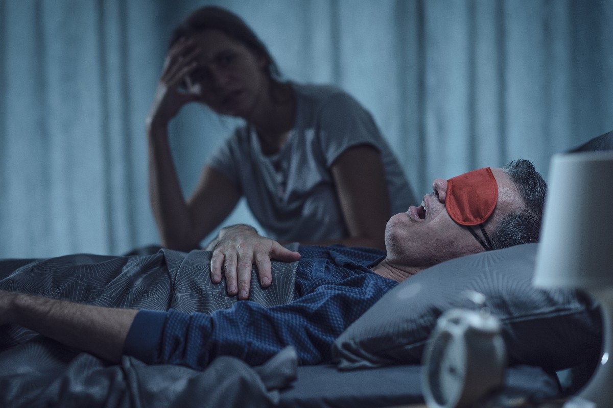 Una moglie sente il marito russare con una maschera da notte rossa