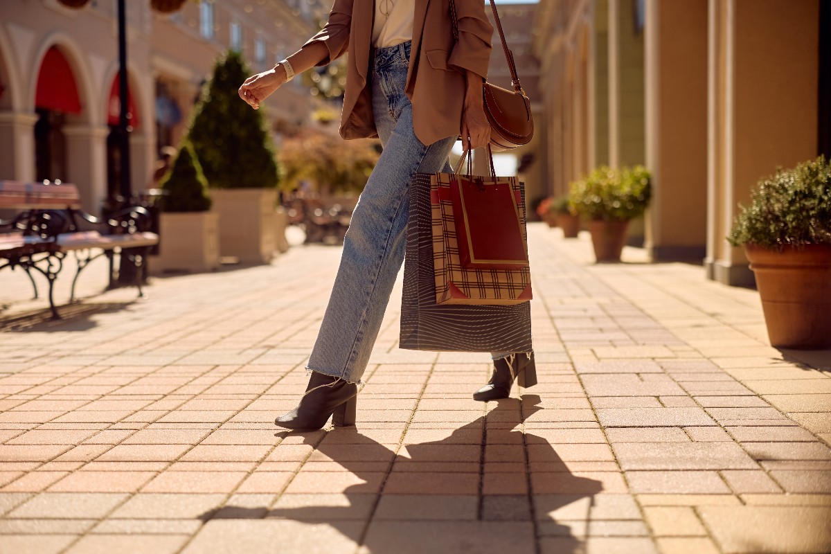 Ragazza stilosa con in mano delle borse da shopping.