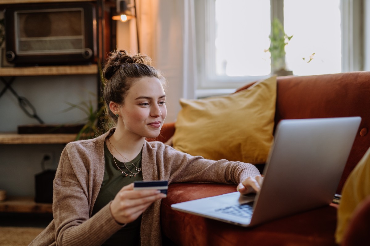 Ragazza intenta a fare shopping online nel proprio salotto.