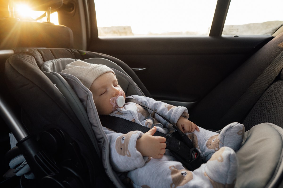 Neonato che dorme nel seggiolino auto.