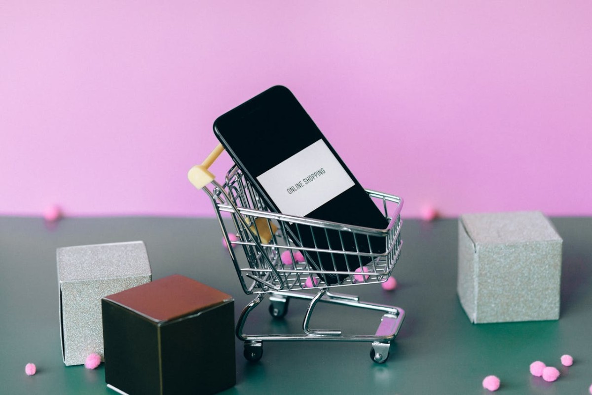 Smartphone dentro un piccolo carrello della spesa.