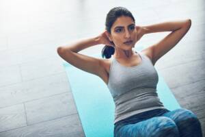 Una donna con una canottiera grigia che fa gli addominali