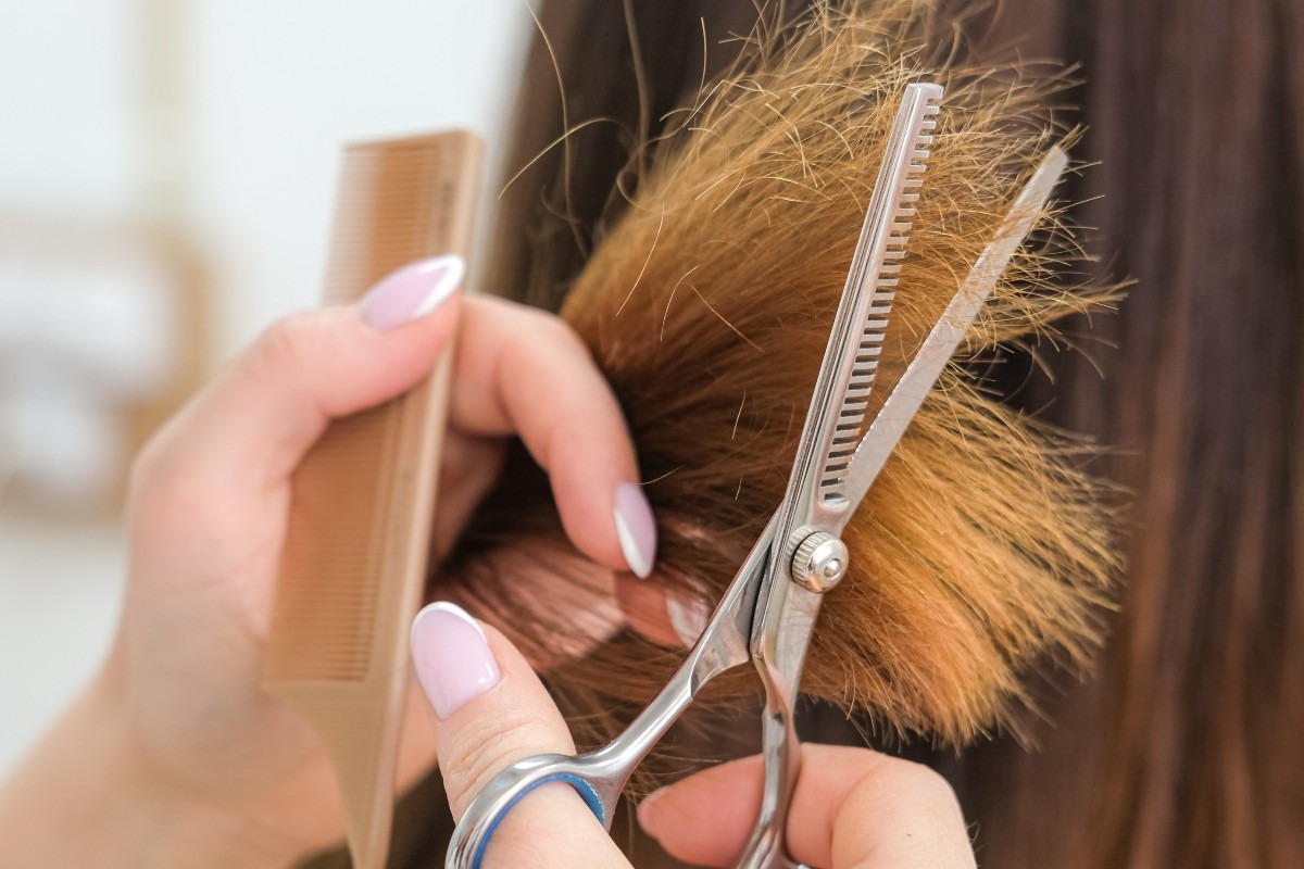 Una donna taglia con le forbici le punti dei capelli rovinate