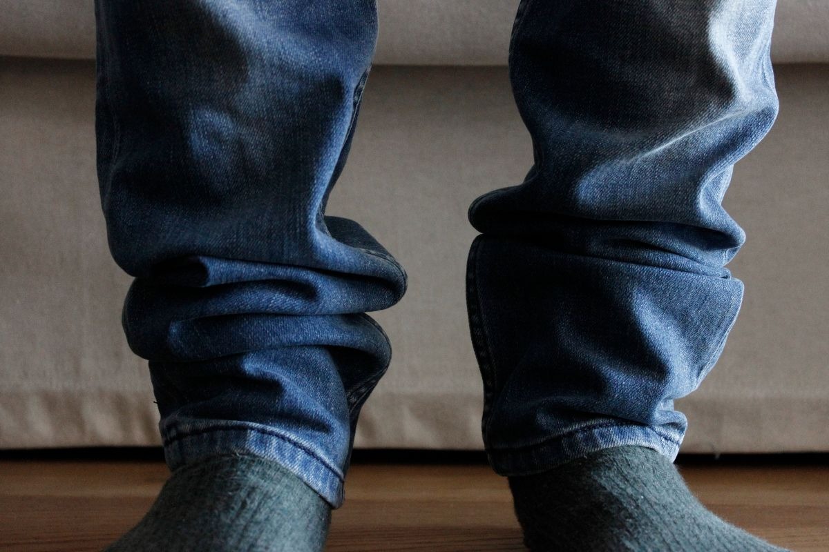 Un uomo con dei jeans blu scuri lunghi